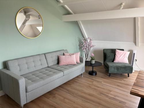 a living room with a couch and a mirror at De Toerist Thuis Bij De Sluis in Spaarndam