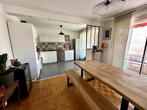 Il comprend un salon avec une table en bois et une cuisine. dans l'établissement Tony Garnier 2 bedrooms - balcony - parking, à Lyon