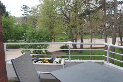 a table and a chair on a balcony with flowers at Ferienwohnungen im Hotel Royal in Timmendorfer Strand
