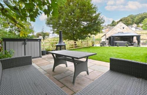 a patio with a picnic table and a grill at Bage Mine Barn in Wirksworth