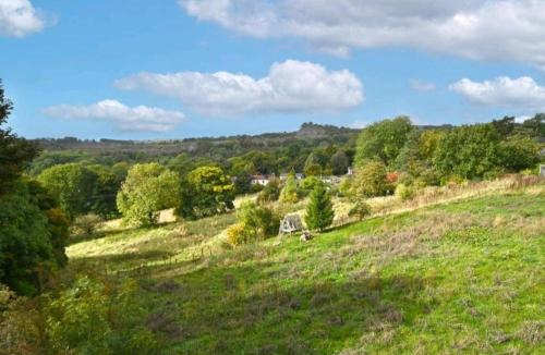 a grassy hill with a house in a field at Bage Mine Barn in Wirksworth