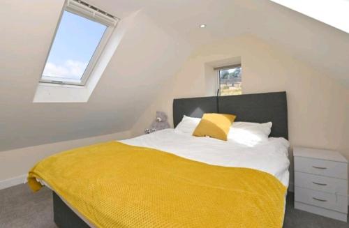 a bedroom with a large bed with a yellow blanket at Bage Mine Barn in Wirksworth