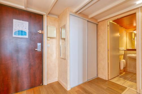 a hallway with a wooden door and a bathroom at Appartement piscine et plage 4p 2ét in Le Croisic