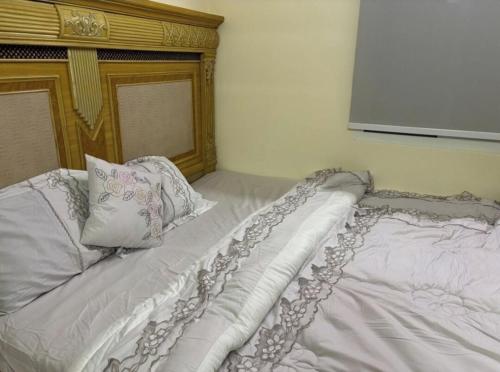 a white bed with a wooden headboard and pillows at Serene Farmhouse Retreat in Ras Al-Khaimah in Ras al Khaimah