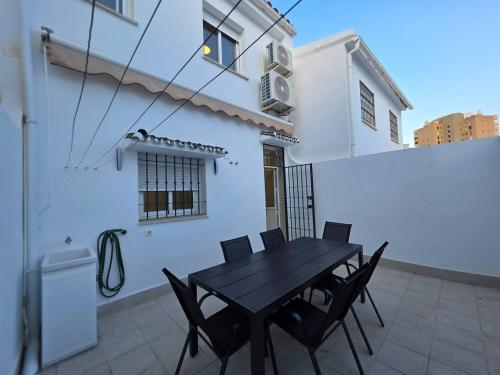 a black table and chairs on the balcony of a house at Chalet Playamar 300m de la playa in Torremolinos