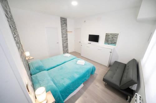 a small bedroom with a blue bed and a chair at En Madrid, amplio, especial grupos o familias in Leganés