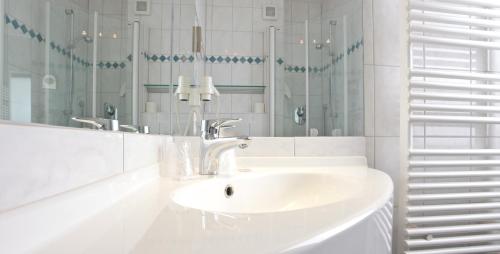 a white bathroom with a sink and a mirror at Waldhotel Bad Soden in Bad Soden am Taunus