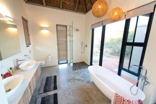 Un baño con dos lavabos y una bañera grande. en Villa Scarabee, en Hoedspruit