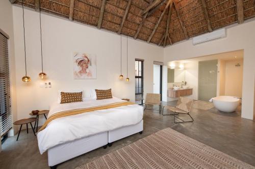 Un dormitorio con una cama grande y una bañera. en Villa Scarabee, en Hoedspruit