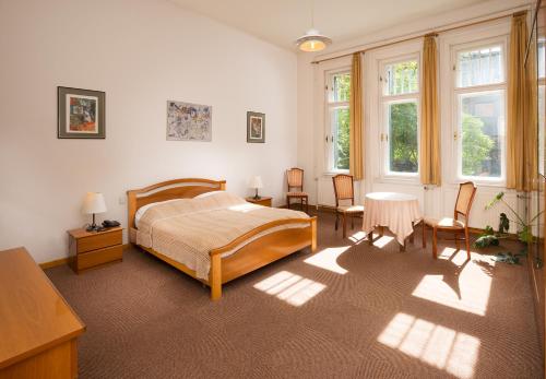 a bedroom with a bed and chairs and windows at Hotel Abel Pension Budapest in Budapest
