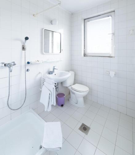 a white bathroom with a toilet and a sink at Hotel Abel Pension Budapest in Budapest