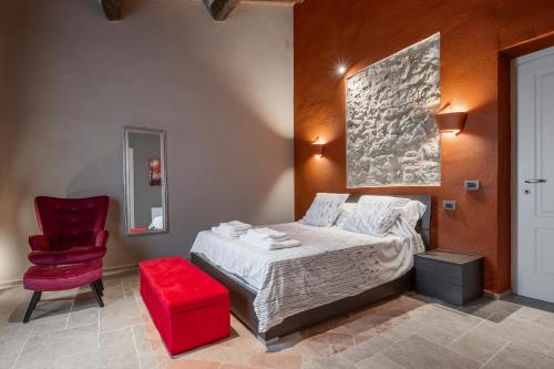 a bedroom with a bed and a red chair at Il rifugio illuminato in Semproniano