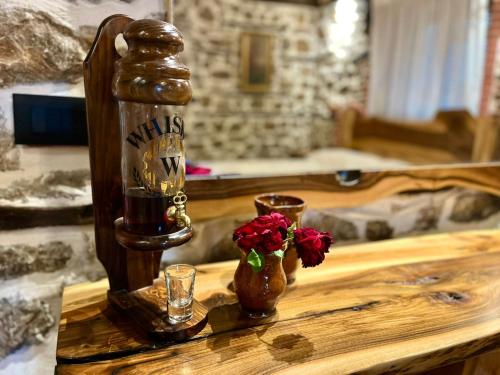 a wooden table with a bottle and two glasses and flowers at Vechia Villa Mitllari in Tushemisht