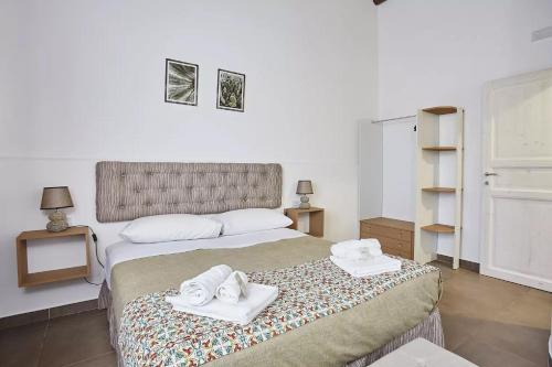 a bedroom with a bed with two towels on it at Casale Sammartano Apartments in Ummari