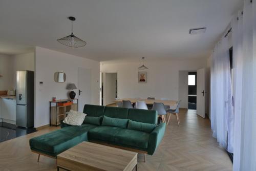 a living room with a green couch and a table at Maison Noé Climatisation individuelle par pièce proche du centre-ville in Ruoms