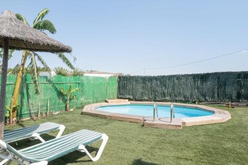 a swimming pool with two lawn chairs and aiki at Villa Guerrero in Conil de la Frontera