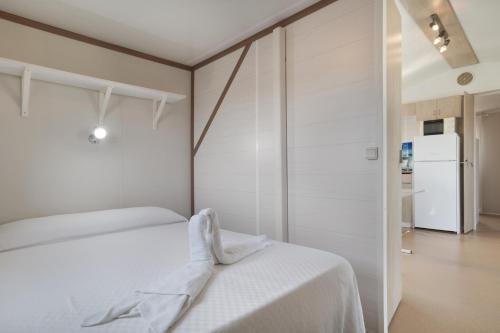 a white bedroom with a bed and a refrigerator at Villa Guerrero in Conil de la Frontera