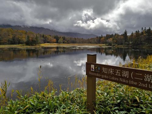 a sign in front of a lake with a mountain at Hermit 知床 in Shari