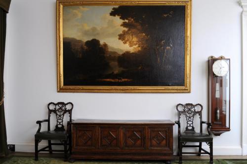 a painting hanging on a wall with two chairs and a dresser at The South Wing in Acharn