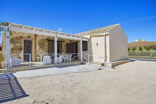 a white house with a porch and white chairs at Casale Sammartano Apartments in Ummari