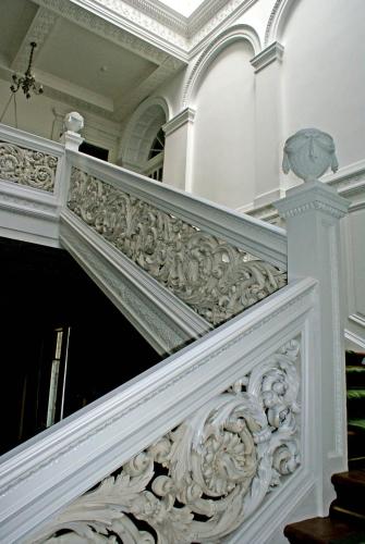 an ornate staircase in a building with a white railing at The South Wing in Acharn