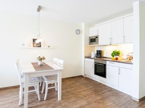 a kitchen with white cabinets and a table and chairs at Kaiserhof 18 Wohnung 16 in Kellenhusen