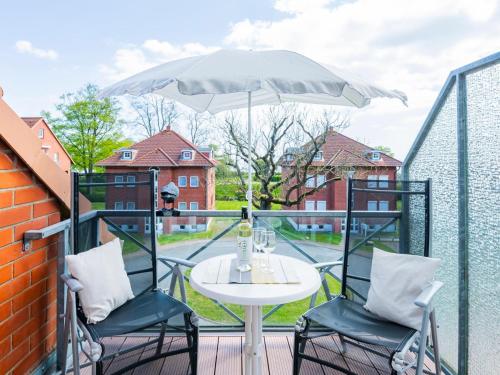 a table and chairs on a balcony with an umbrella at Kaiserhof 18 Wohnung 16 in Kellenhusen