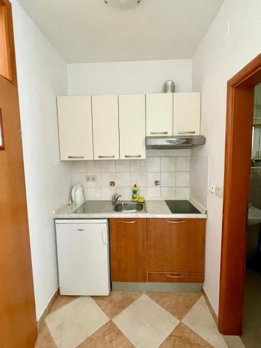 a small kitchen with white cabinets and a sink at Apartments Grbic in Mlini