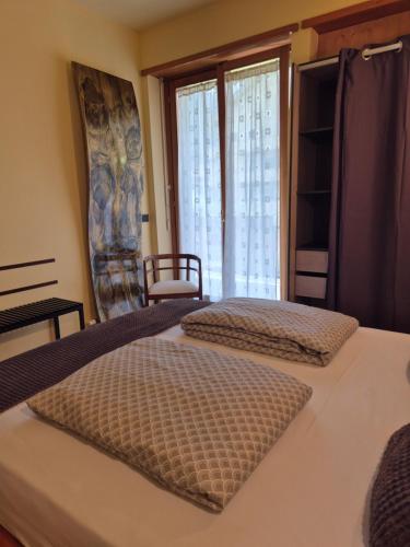 two beds in a room with a window at Il Rosone in Tirano