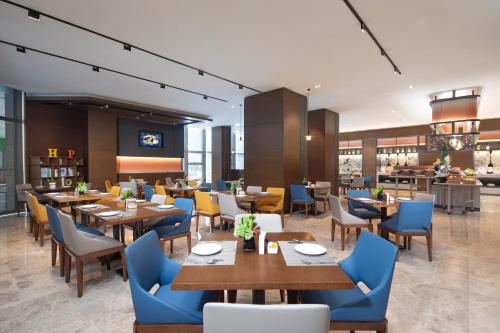 a restaurant with wooden tables and blue chairs at Hampton by Hilton Chengdu Wuhou Waishuannan in Chengdu