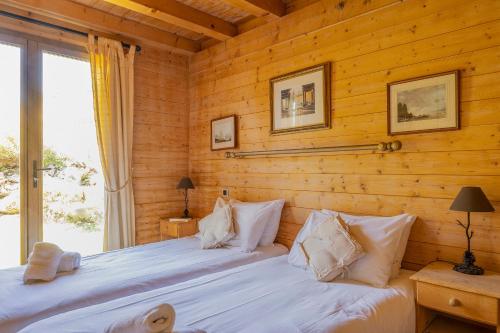 deux lits dans une chambre aux murs en bois dans l'établissement Chalet Mélèze, aux Gets
