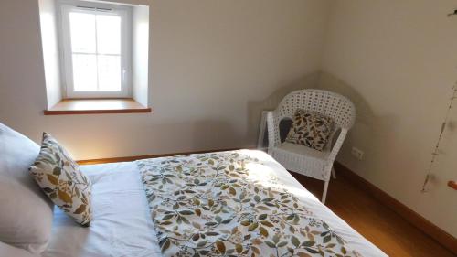 a bedroom with a bed and a chair and a window at Calme et confort en Charente , Gîte Les Vignes avec piscine in Saint-Médard