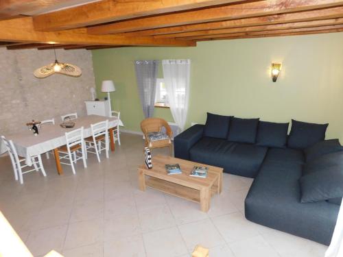 a living room with a blue couch and a table at Calme et confort en Charente , Gîte Les Vignes avec piscine in Saint-Médard