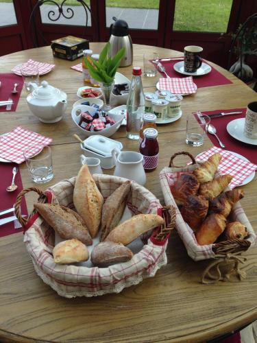 a table with a basket of bread and pastries on it at La Ferme des Templiers de Fléchinelle in Enquin-les-Mines