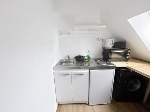 une petite cuisine avec un évier et un micro-ondes dans l'établissement Le Mary - Côté Mairie, à Compiègne