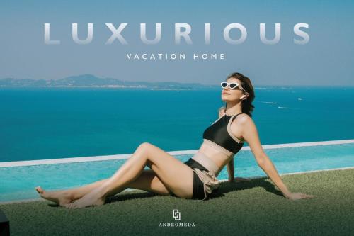 a woman in a bikini sitting on the grass by a pool at Luxury Sea View High Floor Best Stay in Pattaya South