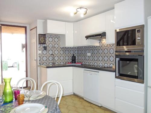 une cuisine avec des placards blancs et une table avec une table dans l'établissement Holiday Home Le Lagon-1 by Interhome, à Saint Cyprien Plage