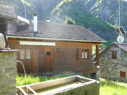 ein kleines Holzhaus vor einem Berg in der Unterkunft Chalet Rustico Fortuna by Interhome in Madra