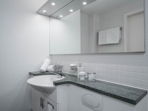 a white bathroom with a sink and a mirror at Apartment Double Room Modern-11 by Interhome in Ascona