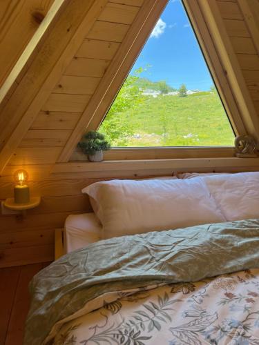 a bed in a room with a large window at Grlo Sokolovo A-Frame Cottage - Mountain Retreat near Podgorica in Korita