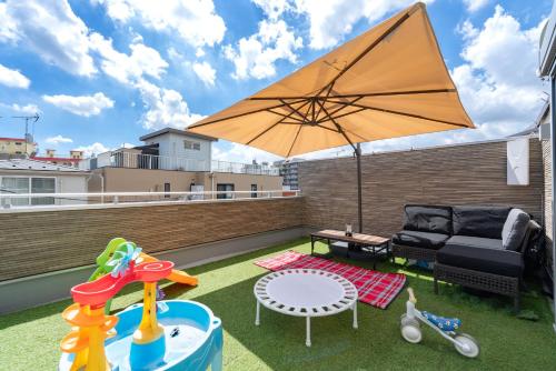 a patio with a couch and an umbrella on a roof at KR family terrace in Tokyo