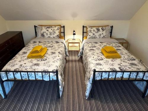 a bedroom with two beds with yellow towels on them at Holiday Home Harlosh by Interhome in Roag