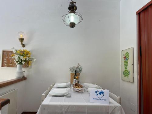 a white dining room with a table and a light fixture at Appartamento tra Verde e Mare by Holiday World in Punta Ala