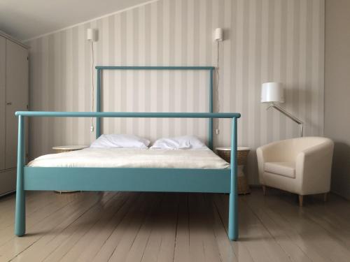 a bed with a blue frame and a chair in a room at Guest House Vasara in Nida