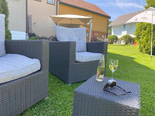 two wicker chairs and a glass of wine on a table at Hotel Landgasthaus Neues Bild, Eggerstanden in Appenzell