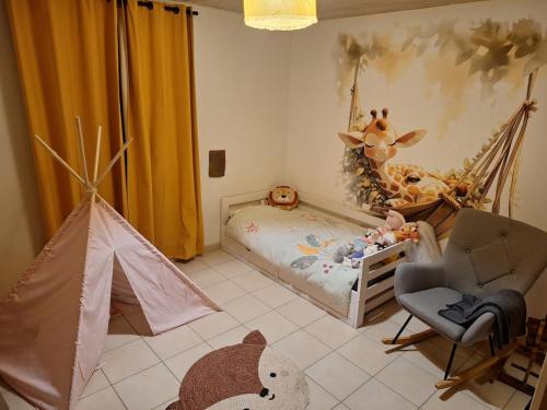 - une chambre pour enfants avec un lit et une chaise dans l'établissement Belle maison de campagne, à Puymiclan