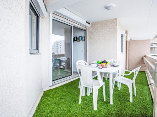 une table et des chaises blanches sur un balcon avec pelouse verte dans l'établissement Apartment Copacabana-32 by Interhome, à Canet