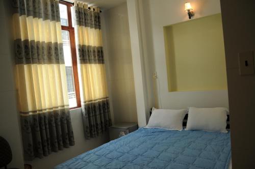 a bedroom with a blue bed and a window at Bien Khoi Mini Hotel in Hue