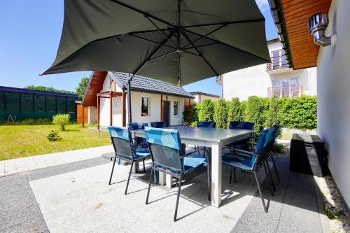 a table with chairs and an umbrella on a patio at Dwie Sowy by Baltic Home in Międzyzdroje