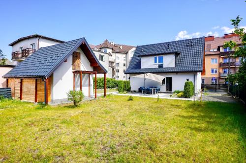 Una pequeña casa en un patio con edificios al fondo. en Dwie Sowy by Baltic Home, en Międzyzdroje